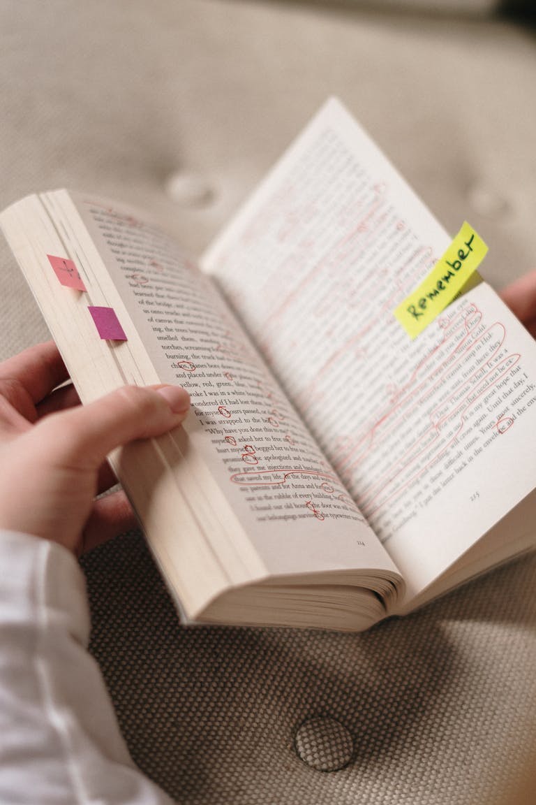 Close-up of a book with annotations and sticky notes with 'Remember'.